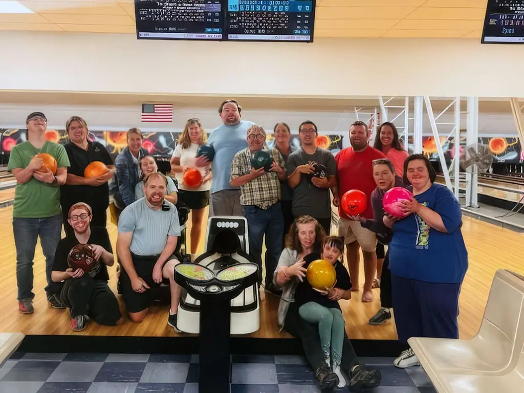 A large group at a bowling alley holding up their bowling balls