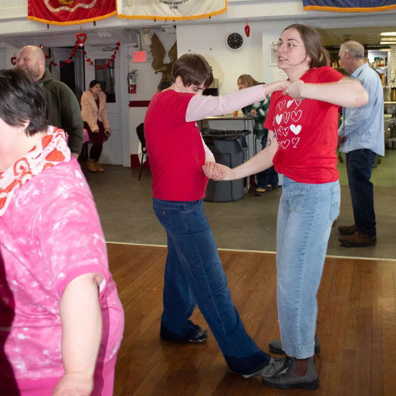 Two dancers in red shirts swinging each other around the dance floor at a Zack’s Place dance