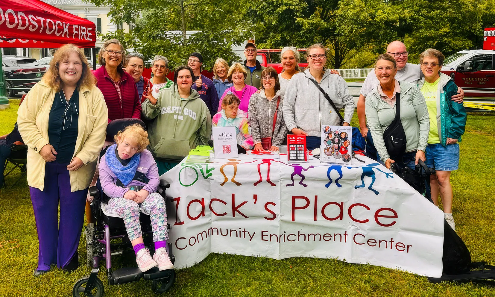 Zack's Place participants, staff and friends gathered behind the Zack's Place banner on the Woodstock green