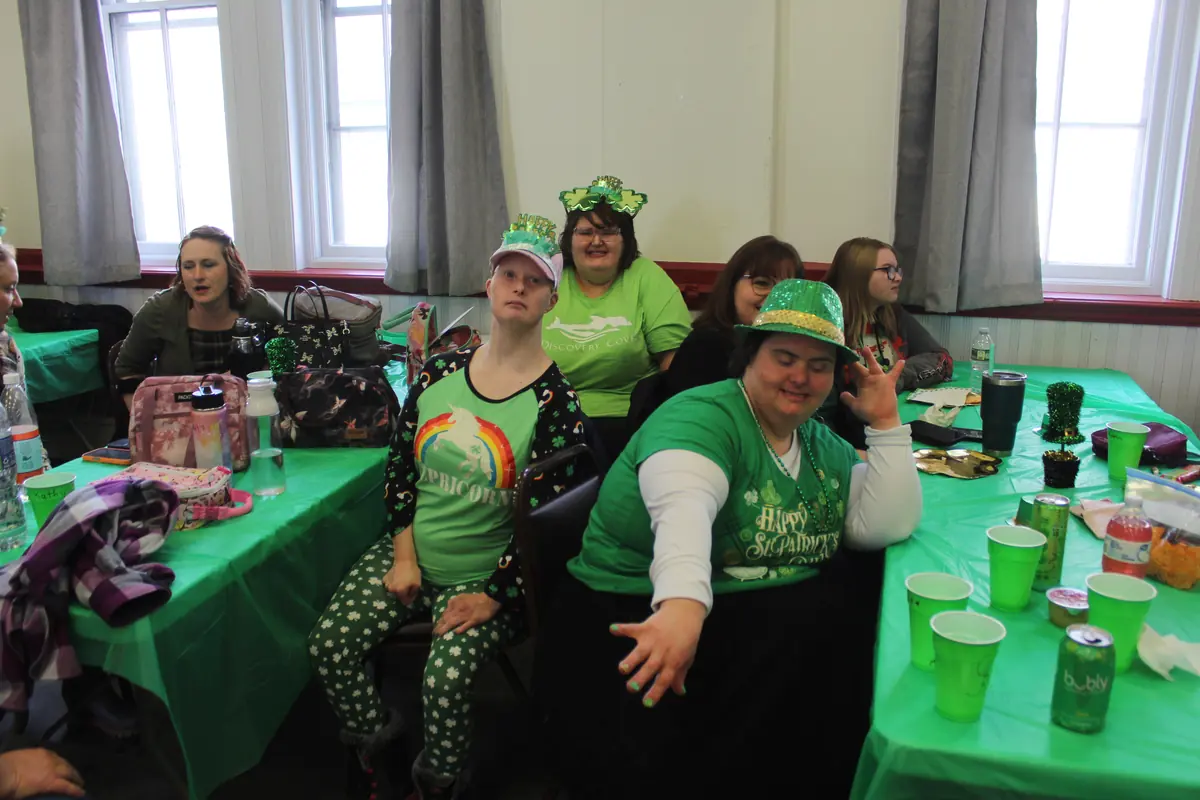 Participants in green hats and shirts celebrating together at a St. Patrick’s Day party
