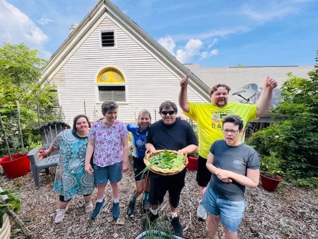 Participants cheering in the garden, one holding a bowl of freshly picked greens